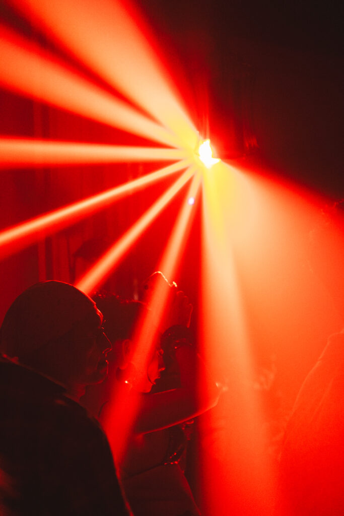 Silhouette of partygoers illuminated by bright red light beams at an underground rave in Davao