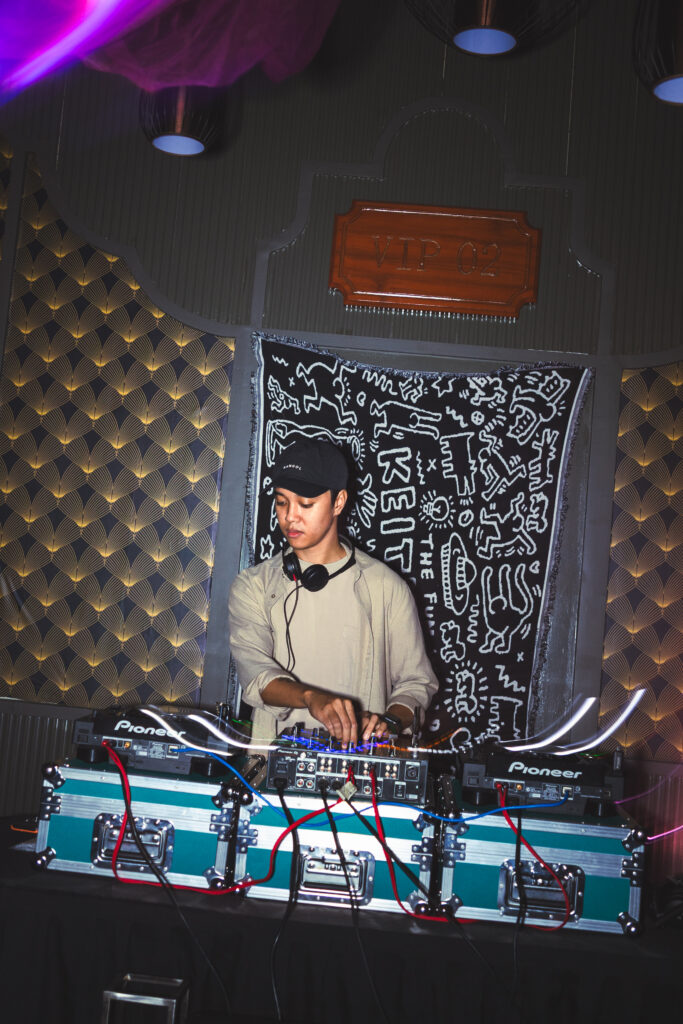 DJ Dik mixing music under low lights at the We Can't Relate Tago Stage