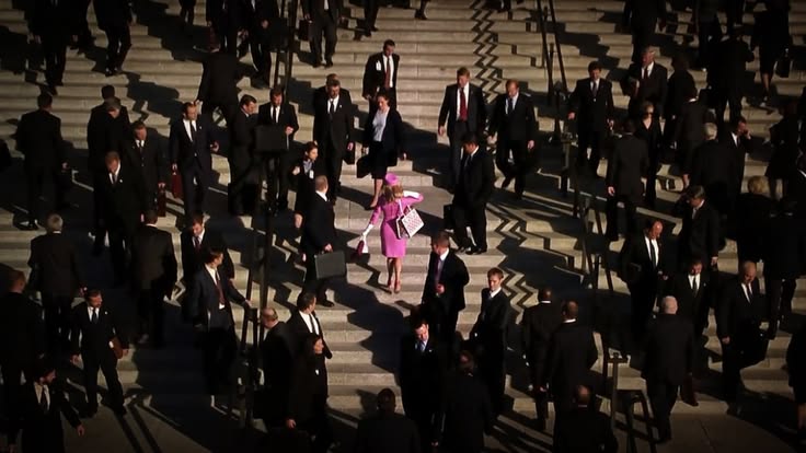 Elle Woods in bright pink walking down busy steps among business professionals