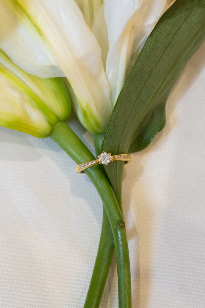 Aveline Cathedral Pavé Ring with lab grown diamond resting on white calla lily stem